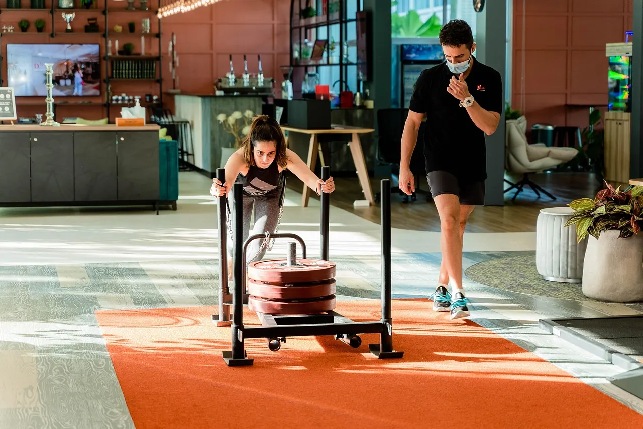 Coach qui accompagne une cliente pendant une poussée de traîneau en salle