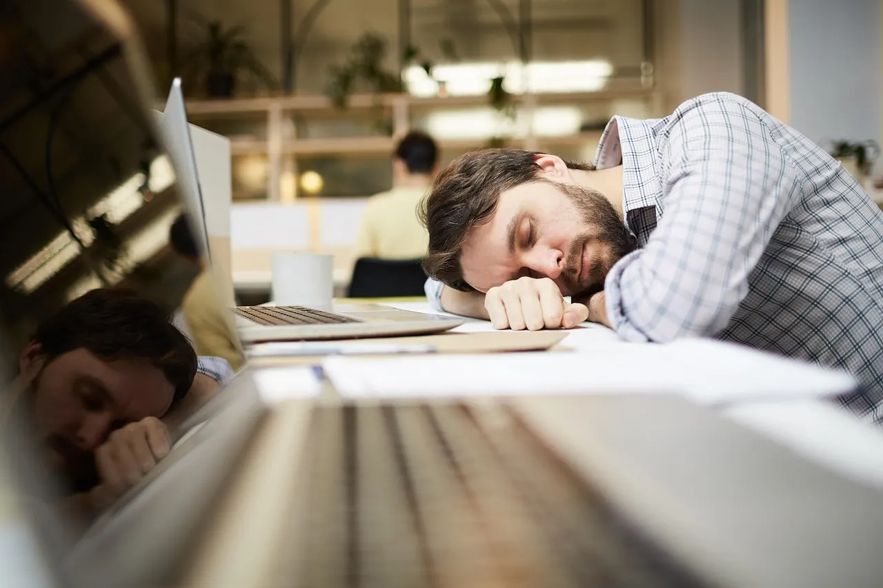Homme endormi sur son ordinateur au bureau en début d'après-midi